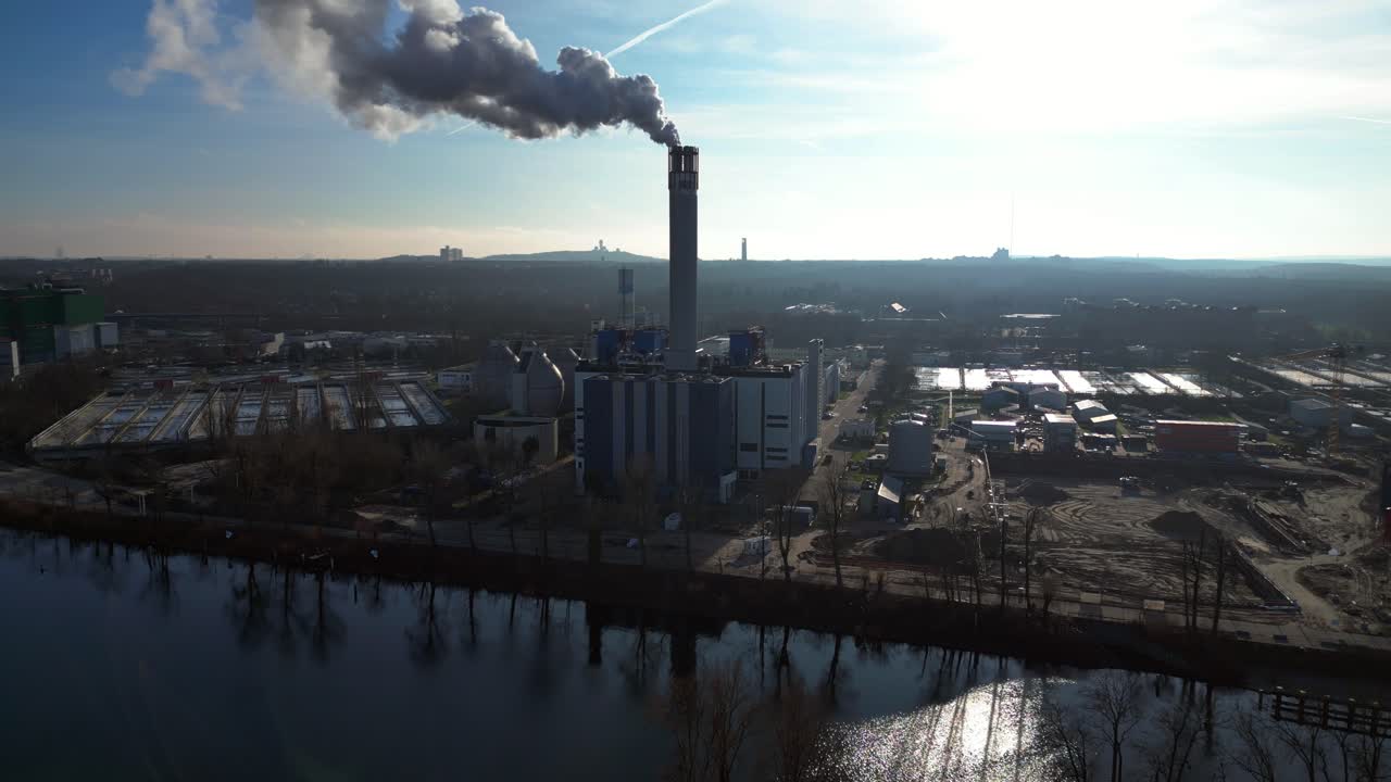 Waste to energy plant emitting smoke from its chimney, located near an urban area, environmental impact of waste. Unique aerial view flight static tripod hovering drone