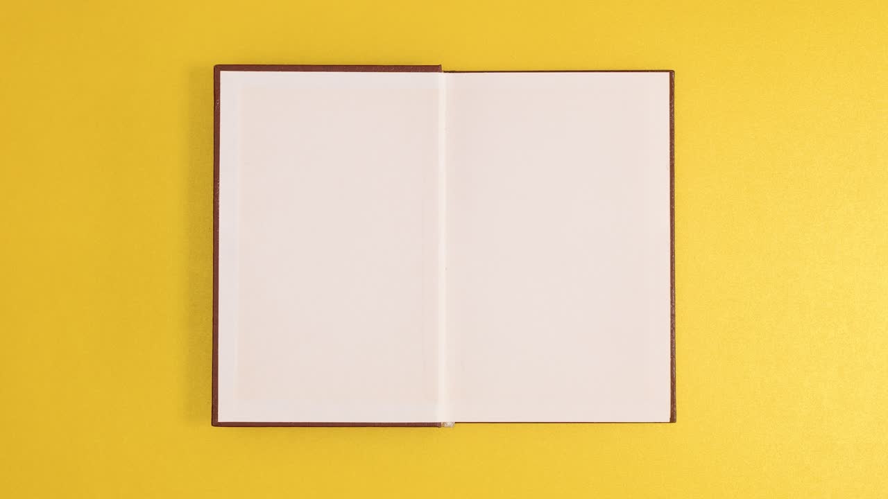 Brown vintage hardcover book appear and open with copy space on golden background. Stop motion flat lay