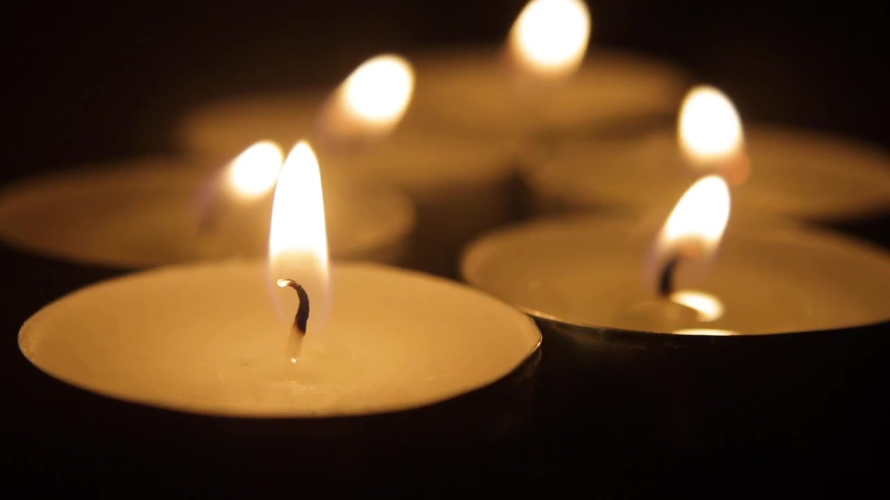 Un gruppo di piccole candele che vengono spente, trasformando la scena nell'oscurità.