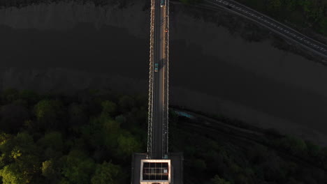 aerial: birds eye of car driving over clifton suspension bridge bristol city england at sunset