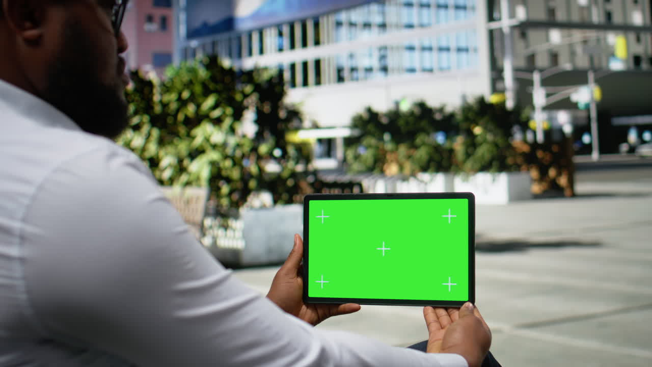 Horizontal green screen with black man sitting on a downtown bench