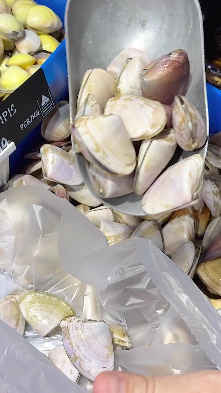 Customer scoops clams into a plastic bag