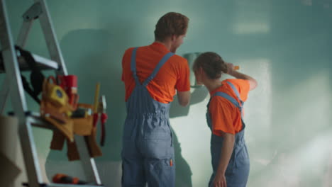 cheerful woman diving under man hand indoors. couple during home renovation.