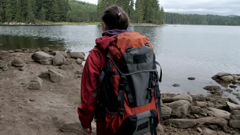 slow motion of a young tourist woman passing by a lake.