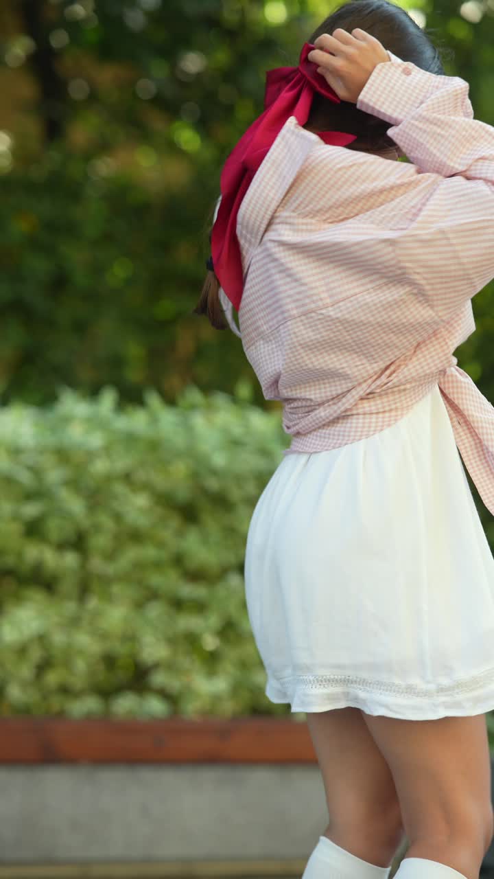 joven con una camisa a cuadros rosa y blanca y un vestido blanco en un parque