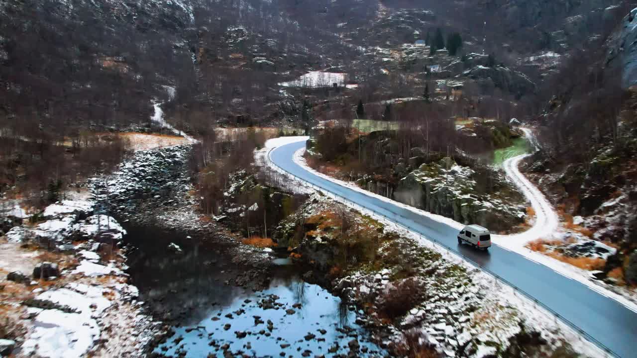 coche conduciendo en una carretera sinuosa a través de un paisaje montañoso nevado en noruega, vista aérea