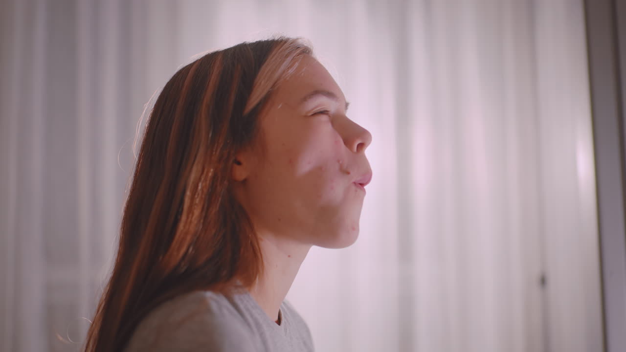 Side view of lady savoring sausage roll with eyes closed in enjoyment, hands holding pastry delicately, warm indoor light highlighting peaceful moment of eating snack reflecting comfort