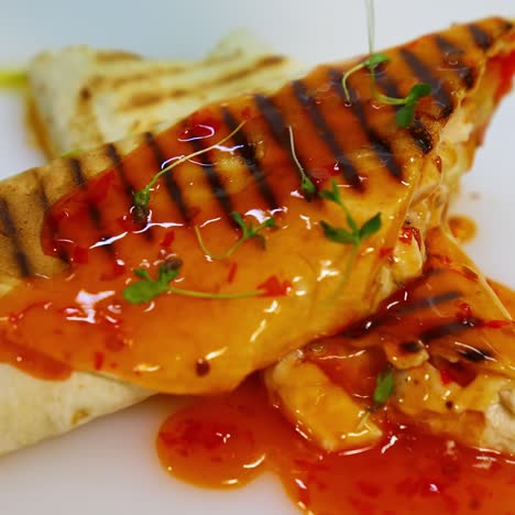 shawarma or doner kebab on white table poured with souce. pita roll is made with tortilla, beef, tomato, onion and lettuce