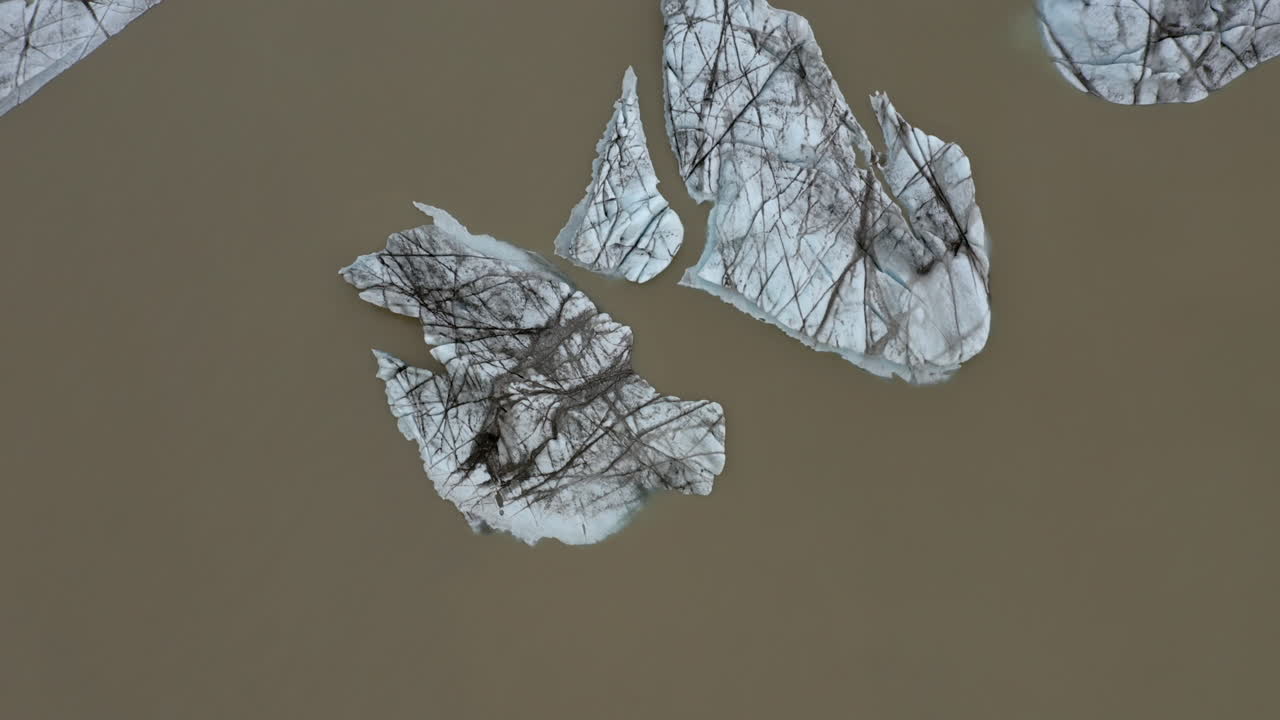 Aerial: Rising top down view of icebergs floating in a lagoon