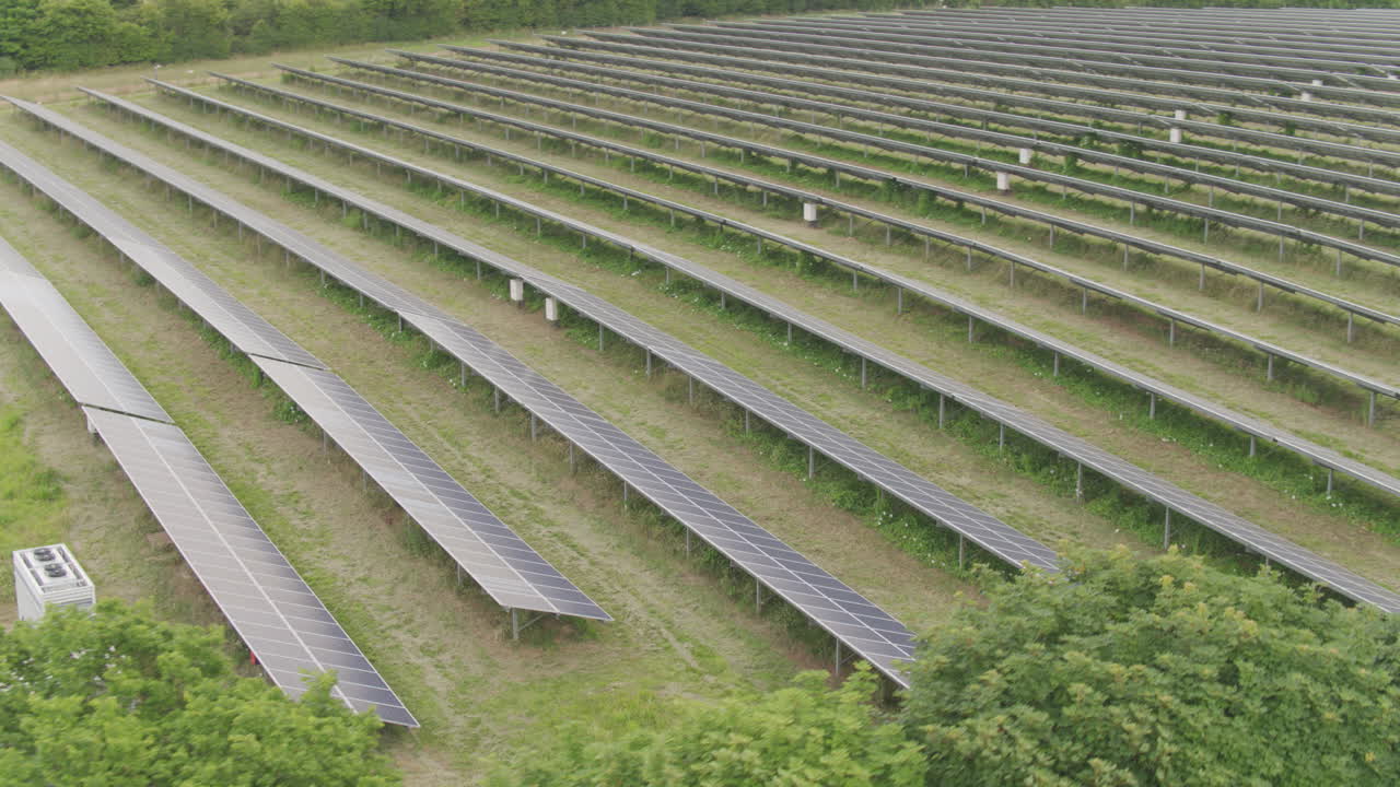 воздушный полет большой фермы солнечных панелей среди зеленых английских полей и деревьев в сельской местности