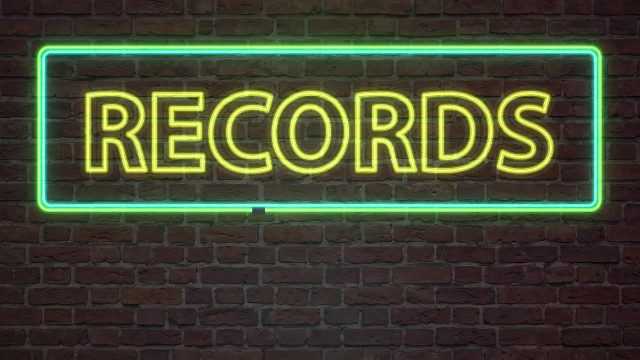 Yellow neon text glows inside a green frame against a dark brick background.