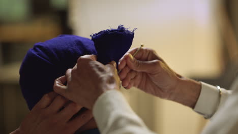 toma de estudio de cerca de un hombre sikh mayor ayudando a un hombre sikh más joven a atar la tela para el turbante contra un fondo plano tomada en tiempo real 2