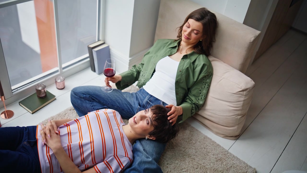 Migliori amiche rilassate che parlano insieme, sentendo un legame emotivo in un primo piano a casa.