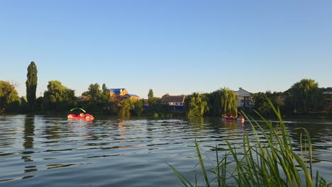 pedal boats floating on a calm lake at sunset in a countryside village