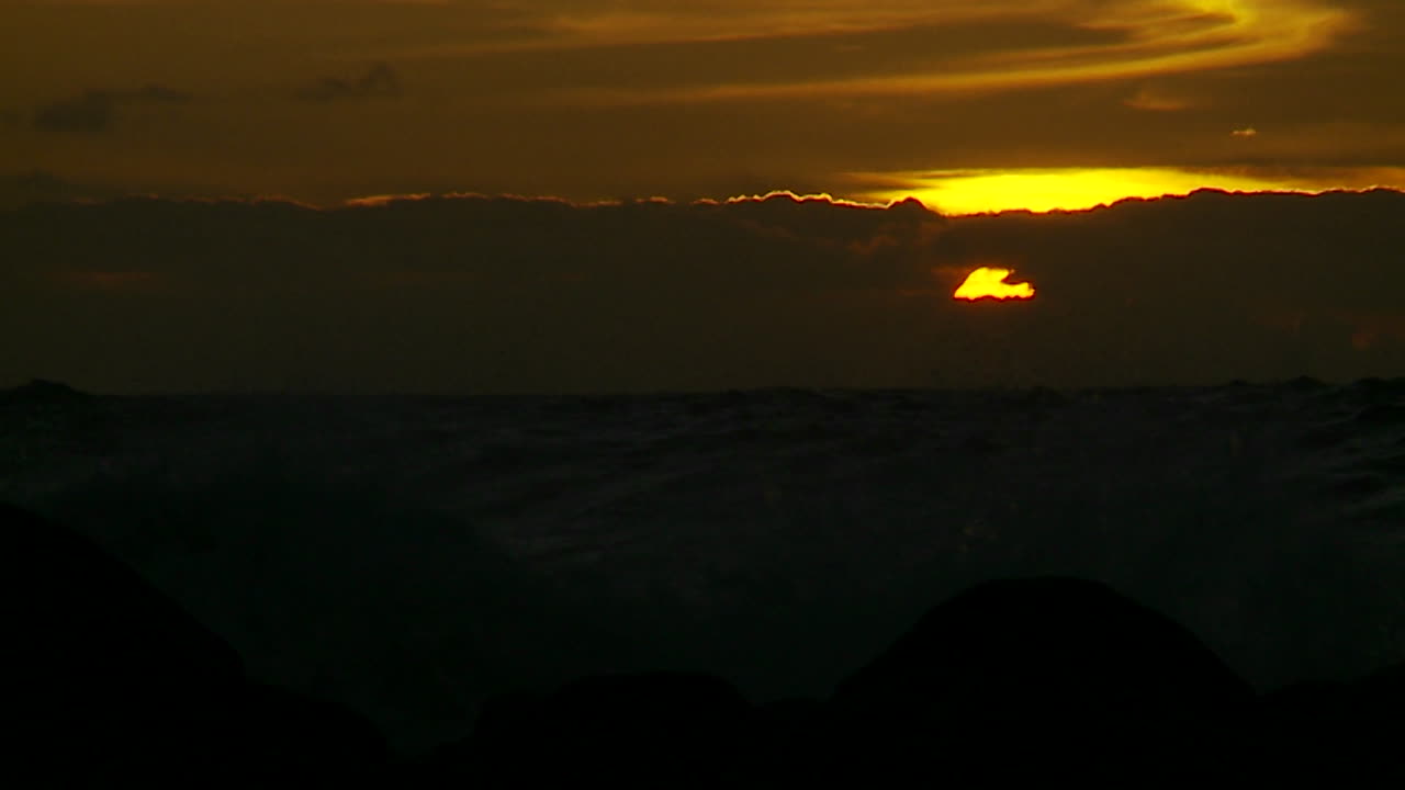 Der Sonnenuntergang hinter Wellen, die sich in Zeitlupe bei Sonnenuntergang brechen 6