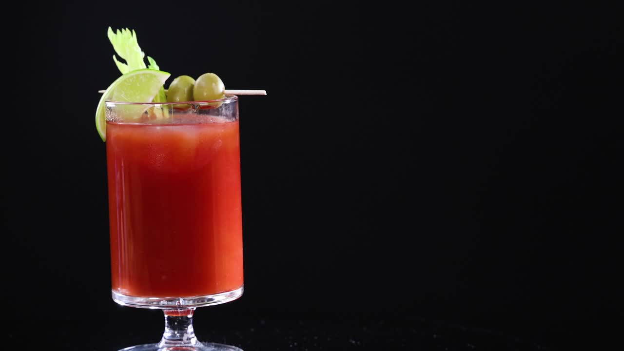 A series of Bloody Mary cocktails with garnishes on a black background, highlighting vibrant colors and elegant presentation