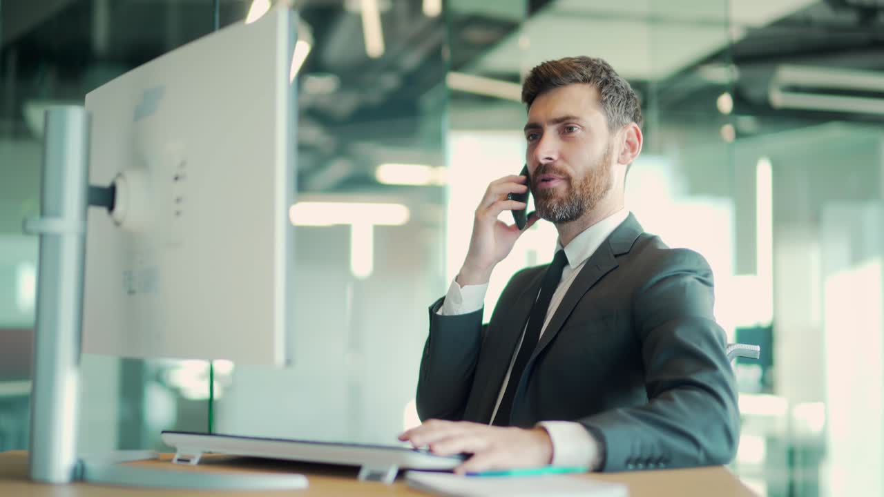 business confident man talking on cellphone sitting at desk in modern office. Caucasian male businessman worker in suit