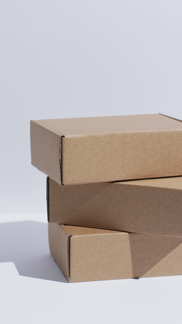 Vertical video of stacked cardboard boxes with copy space over white background