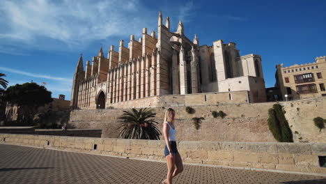 Girl-is-walking-in-front-of-the-Catedral-in-Palma-,-Mallorca