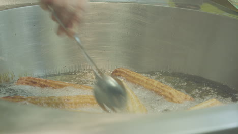 a woman frying farturas in deep oil at a portuguese summer village festival