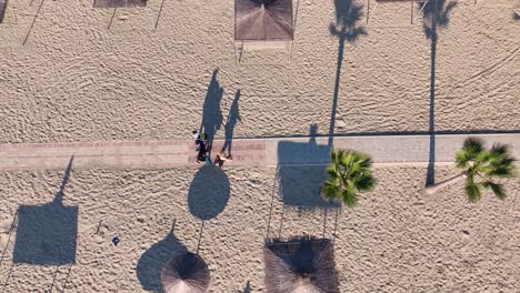 Areal-shot-of-people-walking-on-a-sandy-beach-towards-the-beach