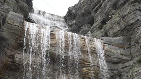 waterfall with water falling down the rocky cliff slow motion static shot, singapore