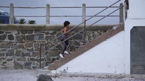 Mixed-race-woman-running-on-staircase-on-docks
