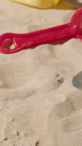 video concepto de vacaciones de verano vertical con juguetes de niño cubo y pala en la playa de arena