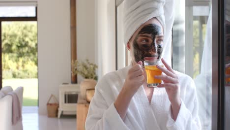 Happy-caucasian-woman-with-mask-drinking-tea-at-window-in-slow-motion