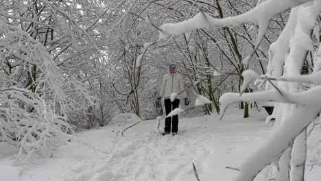 cheerful woman playing snow in winter forest with dense tree branches in background