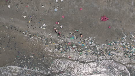 top down aerial shot of villagers in southeast asia collecting plastic waste from beach