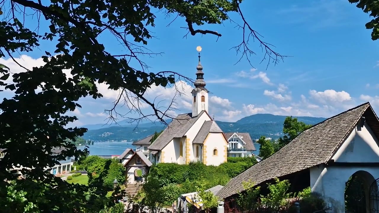 Villaggio di Maria Wörth, Austria. Chiesa Cattolica del Rosario su una collina sopra il lago Wörthersee in una soleggiata giornata estiva.