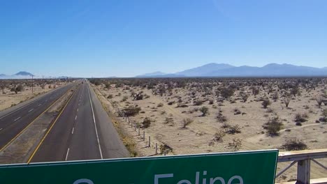 view of a drone flying towards over a sign on a highway that says "bienvenidos a san felipe