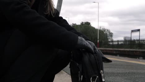 business woman looking in briefcase on train platform medium shot