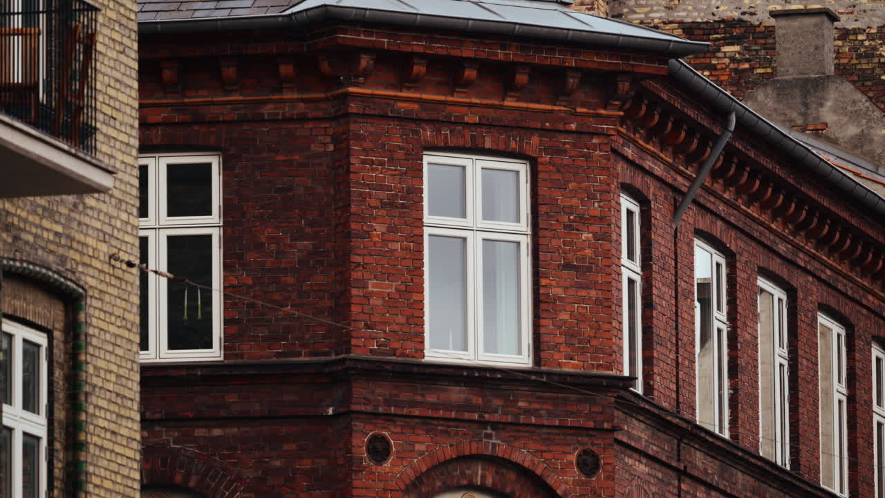 Old brick building facade showing arched windows and a balcony. Copenhagen, Denmark