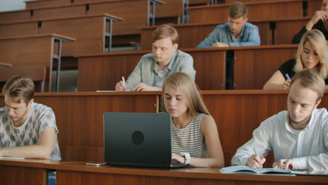 Eine-Große-Gruppe-Multiethnischer-Studenten-Arbeitet-An-Ihren-Laptops,-Während-Sie-Im-Modernen-Klassenzimmer-Einer-Vorlesung-Lauschen.-Kluge-Junge-Leute-Studieren-An-Der-Universität.