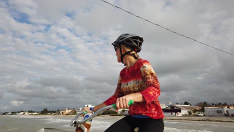 closeup of mature woman riding a cruiser bicycle with a lighthouse and blue sky in the background