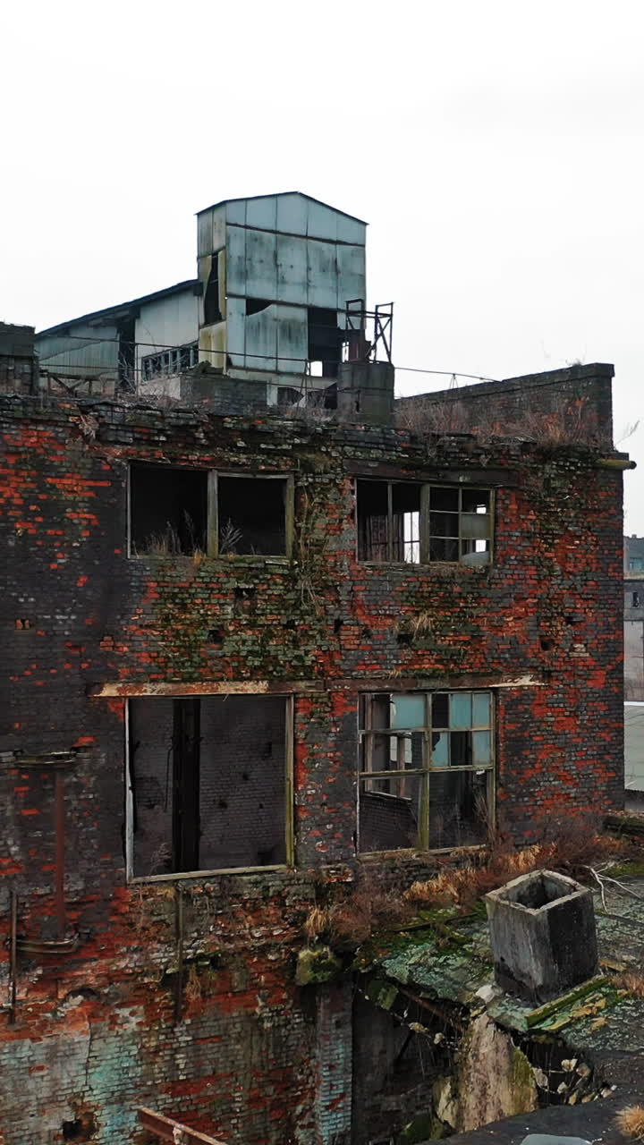 Abandoned factory with different buildings in industrial zone on the outskirts of the city? in aerial view. Vertical video