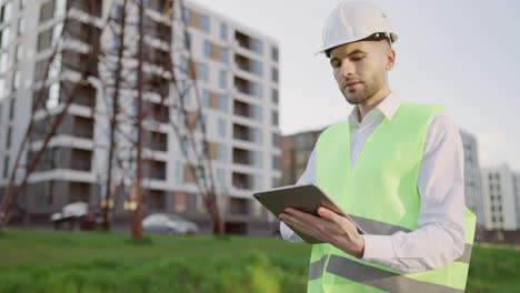 engineer in safety gear using a tablet at a construction or development site
