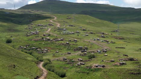 Heavy-commercial-truck-drives-winding-dirt-road-thru-Lesotho-village