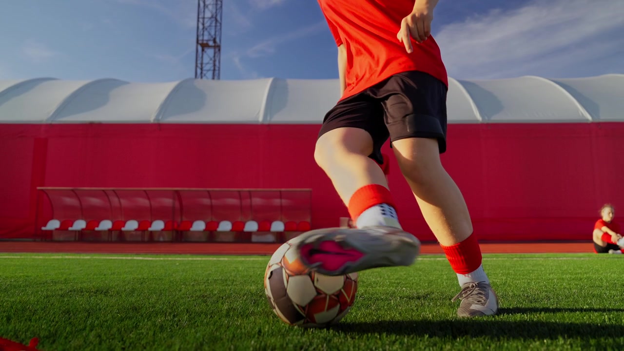 Jóvenes futbolistas femeninas practicando ejercicios de regate en un campo al aire libre.