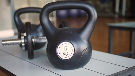 closeup of a black kettlebell and dumbbell on a table