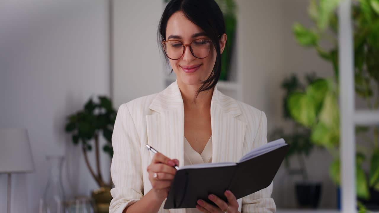 una mujer de negocios feliz escribe sus pensamientos en un cuaderno.