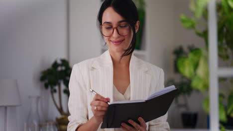 happy businesswoman writes thoughts in notebook