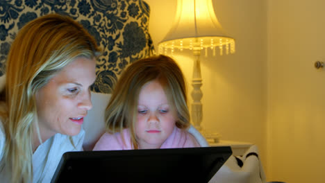 Vista-Frontal-De-Una-Joven-Madre-Caucásica-Y-Su-Hija-Usando-Una-Tableta-Digital-En-El-Dormitorio-En-Casa-4k