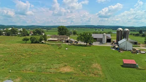 una vista aérea de las tierras de cultivo amish con graneros y silos en un día soleado de verano
