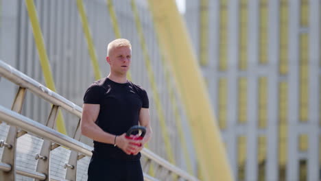 half body shot of young blond man working out with kettlebell outdoors