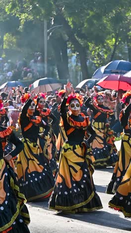 day of the dead parade: women in calavera costumes dance through the streets
