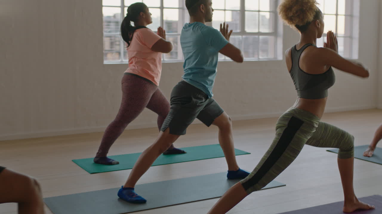 yoga class of young healthy people practicing traingle pose enjoying fitness lifestyle exercising in studio at sunrise
