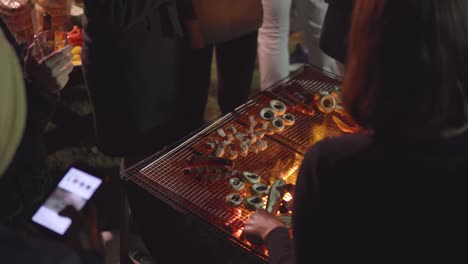 view from top and behind the shoulders of people on grilling mushrooms, sausage, chicken, eggplant on bbq in front of the house in a garden